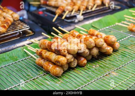 Begeben Sie sich auf eine kulinarische Reise durch Thailands Isan-Region mit diesem herzhaften Leckerbissen! Stolz hängen Sie an einem geschäftigen Händlerstand, diesem traditionellen Schweinefleisch Stockfoto