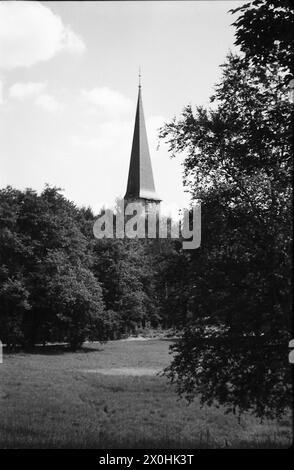 Das Bild zeigt die kleine Kirche in Nikolassee mit ihrem spitzen Turm von der Rehwiesen-Seite. Damals, als Sie den letzten Checkpoint aus Westdeutschland überquerten und die Spitze des Turms sahen, wussten Sie, dass Sie zu Hause waren. Münchner kennen vielleicht das Gefühl, auf die Olympische Autobahn in Richtung München abzubiegen und die Türme der Frauenkirche zu sehen. [Automatisierte Übersetzung] Stockfoto