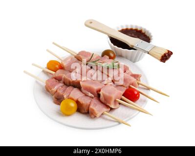 Spieße mit rohen Fleischstücken, Rosmarin, Tomaten und Marinade, isoliert auf weiß Stockfoto