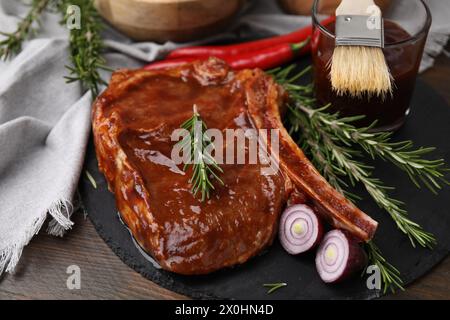 Leckeres mariniertes Fleisch, Rosmarin und Zwiebeln auf Holztisch, Nahaufnahme Stockfoto