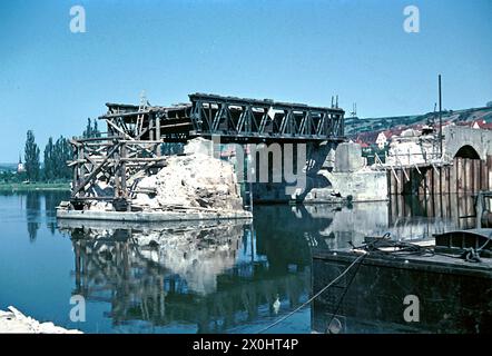 Am 1. April 1945 sprengten deutsche Einheiten Arch 6 in der Mitte der Brücke. In den folgenden Jahren überspannte eine provisorische Holzkonstruktion die Lücke im Gebäude. Der Eröffnung der Neuen Hauptbrücke 1954 folgte der Wiederaufbau der Alten Hauptbrücke, der 1957 abgeschlossen wurde. Durch den Ausbau des Mains zu einer wichtigen Schifffahrtsroute wurden die drei Mittelbögen fünf bis sieben durch einen rund 58 Meter langen Spannbetonbalken ersetzt, der den Main überspannte, der durch das Goßmannsdorfer Stauwerk gestaut wurde. [Automatisierte Übersetzung] Stockfoto