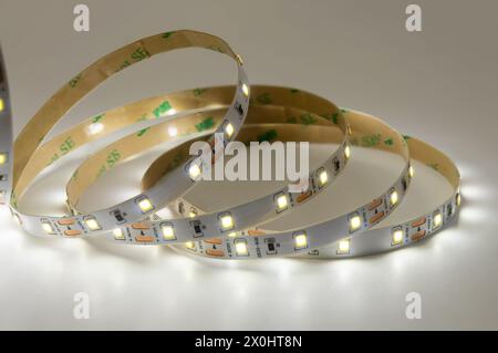 Entdecken Sie die Vielseitigkeit moderner Beleuchtung mit beleuchteten LED-Streifen-Lichtspulen. Weißes leuchtendes LED-Band, in kreisförmigen Formen angeordnet, zeigt Flexibi Stockfoto