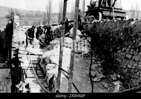 Am 1. April 1945 sprengten deutsche Einheiten Arch 6 in der Mitte der Brücke. In den folgenden Jahren überspannte eine provisorische Holzkonstruktion die Lücke im Gebäude. Der Eröffnung der Neuen Hauptbrücke 1954 folgte der Wiederaufbau der Alten Hauptbrücke, der 1957 abgeschlossen wurde. Durch den Ausbau des Mains zu einer wichtigen Schifffahrtsroute wurden die drei Mittelbögen fünf bis sieben durch einen rund 58 Meter langen Spannbetonbalken ersetzt, der den Main überspannte, der durch das Goßmannsdorfer Stauwerk gestaut wurde. [Automatisierte Übersetzung] Stockfoto