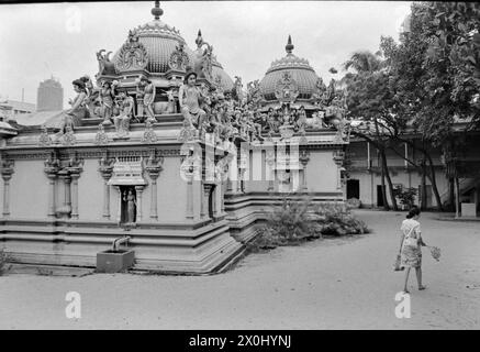 Blick auf einen Hindu-Tempel in Singapur. Die Fassade ist reich mit Figuren und Verzierungen verziert. Im Hintergrund sieht man einen Wolkenkratzer. [Automatisierte Übersetzung] Stockfoto