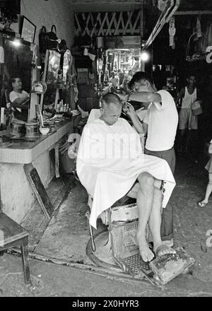 Ein Mann bekommt seine Haare in einem frisierstuhl geschnitten. [Automatisierte Übersetzung] Stockfoto