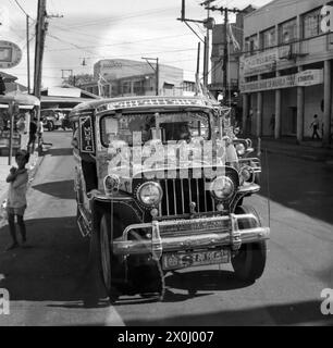 Ein farbenfroh dekoriertes Geländefahrzeug in Manila auf den Philippinen. Daneben ein kleiner Junge. [Automatisierte Übersetzung] Stockfoto