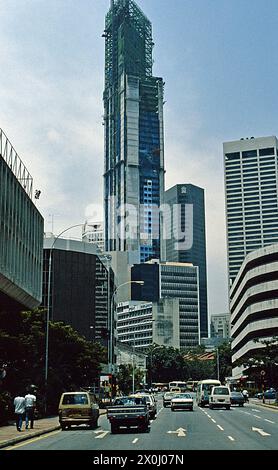 Blick auf moderne Hochhäuser in Singapur. Der höchste von ihnen befindet sich noch im oberen Bereich im Bau. Im Vordergrund ist eine breite Straße zu sehen. [Automatisierte Übersetzung] Stockfoto