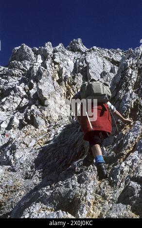 Ein Bergsteiger mit Rucksack klettert den steilen Pfad hinauf. [Automatisierte Übersetzung] Stockfoto