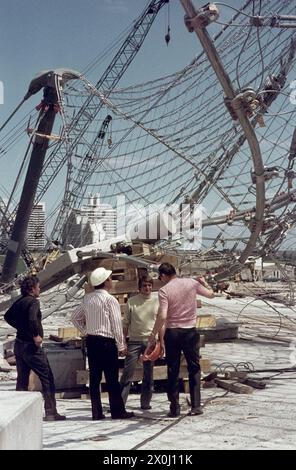 Vier Männer stehen auf der Baustelle unter dem Seilnetz. Die Studentenstadt im Hintergrund. [Automatisierte Übersetzung] Stockfoto