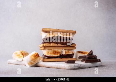 Frisch geröstete Smores mit großen weißen Marshmallows. Köstliches Marshmallow-Sandwich mit Cracker und Schokolade auf grauem Tisch, Nahaufnahme. Stockfoto