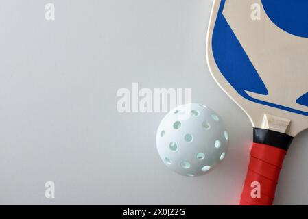 Detail des Pickleball-Schlägers und einer weißen Kugel isoliert auf weißem Tisch. Draufsicht. Stockfoto