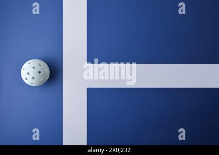 Hintergrund mit weißer Pickleball-Kugel auf einer blauen Spielfläche mit weißen Linien. Draufsicht. Stockfoto