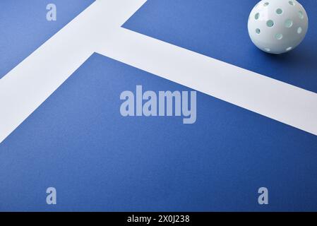 Hintergrund mit weißer Pickleball-Kugel auf einer blauen Spielfläche mit weißen Linien. Erhöhte Aussicht. Stockfoto