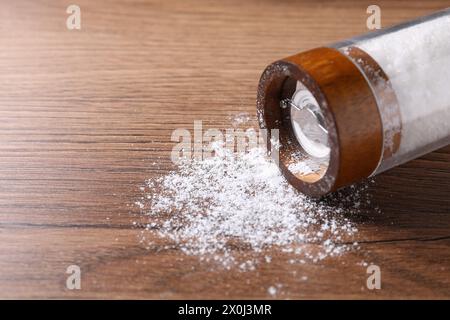 Umgedrehter Shaker mit Salz auf Holztisch, Nahaufnahme. Leerzeichen für Text Stockfoto