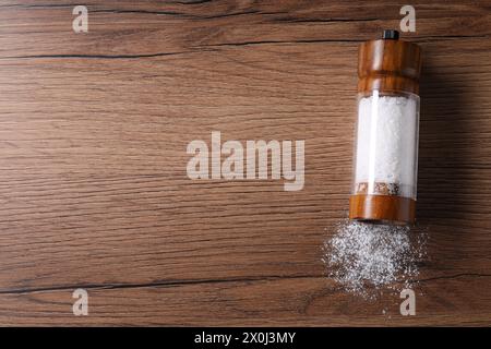 Umgedrehter Shaker mit Salz auf Holztisch, Blick von oben. Leerzeichen für Text Stockfoto