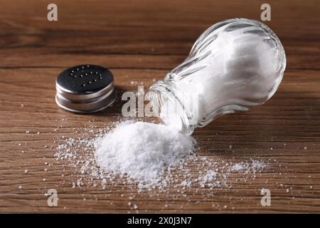Umgedrehter Shaker mit Salz auf Holztisch Stockfoto