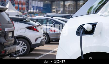Nahaufnahme eines aufladenden Elektroautos auf dem Hintergrund geparkter Autos. Stockfoto