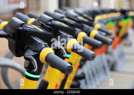 Elektroroller in einer Reihe auf dem Parkplatz. Mietsystem in der Größe, öffentliche E-Scooter auf der Straße Stockfoto