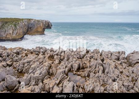 Ein Blick auf die zerklüftete felsige Küste von Los Bufones de Llanes, Asturien, mit scharfen Felsen, die in das ausgedehnte Gewässer ragen. Stockfoto