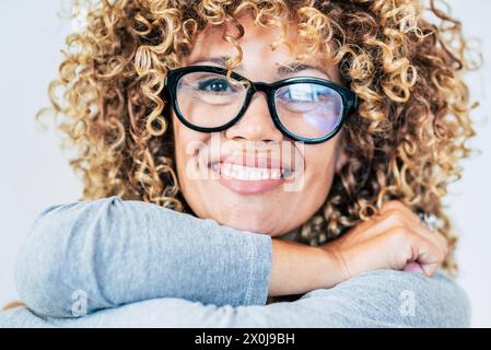 Porträt einer jungen erwachsenen Frau, die in die Kamera lächelt und Brille trägt. Blonde, lockige, lange Haare, Frau, genießt das Leben. Fröhliches und fröhliches Lächeln der Dame. Vorderansicht der Dame mit selbstbewusstem und nettem Ausdruck Stockfoto