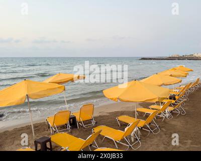 Am Strand von Gouves auf der Urlaubsinsel Kreta stehen abends leere Liegestühle und Sonnenschirme zur Verfügung Stockfoto