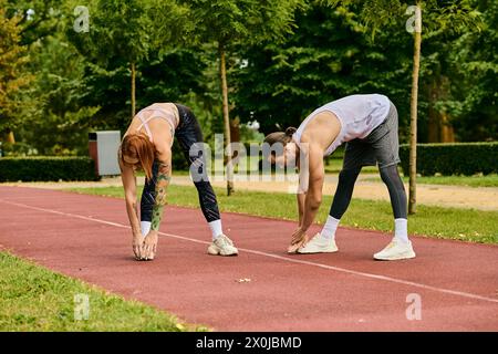 Eine Frau in Sportbekleidung trainiert mit einem Personal Trainer auf der Rennbahn und zeigt Entschlossenheit und Motivation. Stockfoto