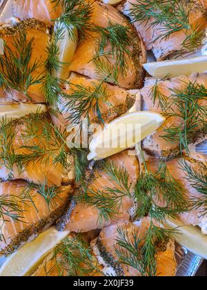 Brotscheiben mit Lachs, serviert mit Dill und Zitronenscheiben auf einer Servierplatte Stockfoto