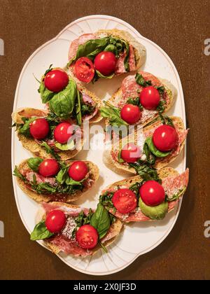 Servierplatte mit ganzen Cocktailtomaten und Mozzarella auf Brotscheiben als Vorspeise Stockfoto