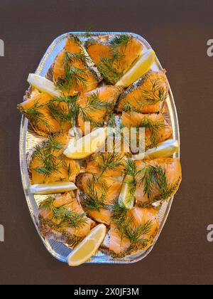 Brotscheiben mit Lachs, serviert mit Dill und Zitronenscheiben auf einer Servierplatte Stockfoto