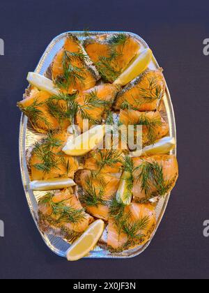 Brotscheiben mit Lachs, serviert mit Dill und Zitronenscheiben auf einer Servierplatte Stockfoto