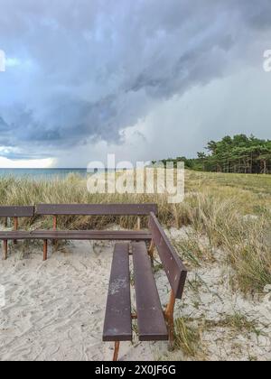 Deutschland, Mecklenburg-Vorpommern, Prerow, Wolkenbildung über der Ostsee, Dünenlandschaft, Holzbank im Vordergrund Stockfoto