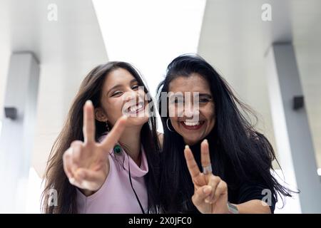 Zwei Erwachsene lateinamerikanische Frauen, Mutter und Tochter mit positiver Einstellung, die Spaß vor der Kamera haben. Konzeptgenerationen und Muttertag. Stockfoto