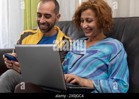 Ein paar lateinamerikanische Freunde arbeiten zu Hause zusammen und sitzen auf dem Sofa Stockfoto