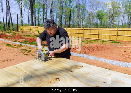 Professioneller Zimmermann beim Schneiden von Holzsperrholz mit elektrischer Kreissäge Stockfoto