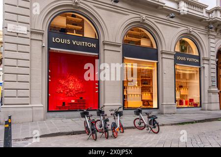 Florenz, Italien - 4. April 2024: Schaufenster des Louis Vuitton Florence Ladengeschäfts auf der Piazza degli Strozzi mit Elektroleihfahrrädern vor dem Hotel Stockfoto