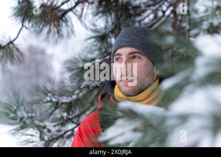 Junger gutaussehender kaukasier, der im Winter im Bergwald wandert. Sport Abenteuer Lifestyle. Trekking in einer verschneiten Landschaft Stockfoto