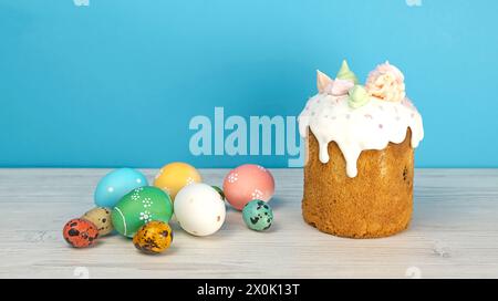 Ostergebäck und farbige Eier auf blauem Hintergrund. Glasierte Osterpanettone und farbige Ostereier. Stockfoto