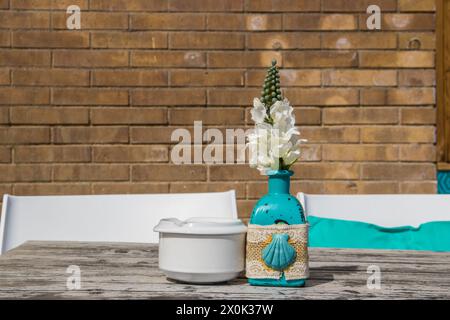 Lagerhaus im Freien. Bei sommerlichen Sonneneinflüssen stehen Stühle und Tische im Freien zur Verfügung. Vase mit den Blumen auf dem Tisch für Sommer-Café. Stockfoto