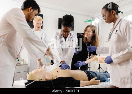 Eine Gruppe medizinischer Mitarbeiter versammelt sich um eine HLW-Trainingspuppe, die lebensrettende Techniken in einer medizinischen Simulation praktiziert. Stockfoto