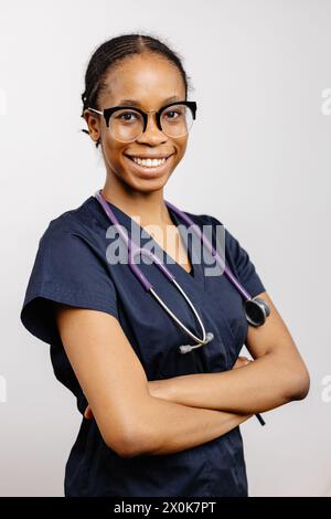 Eine weibliche Pflegekraft, die blaue medizinische Peelings und ein Stethoskop um den Hals trägt, bereit, Patienten in einer klinischen Umgebung zu helfen. Stockfoto