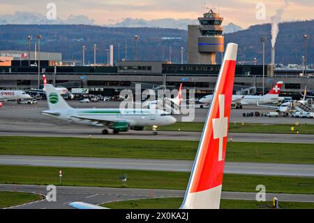 Vertikaler Stabilisator eines Airbus der Fluggesellschaft Swiss International Air Lines mit dem Schweizer Kreuz, dahinter ein weiteres Flugzeug, das zum Start fährt, Zürich Airport, Zürich, Schweiz Stockfoto