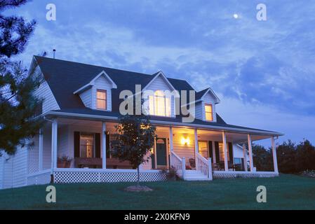 Weißes Haus in ländlicher Umgebung beleuchtet für den Abend mit aufsteigendem Mond, Sommer, Missouri, USA Stockfoto