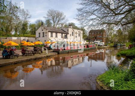 Schmalboote auf dem Shropshire union Kanal vor dem Shroppie fly Pub im Dorf Cheshire Audlem, wo Menschen essen und trinken Stockfoto