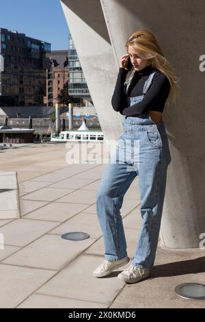 Junge Frau am Telefon, stehend, in der Hafenstadt Hamburg Stockfoto