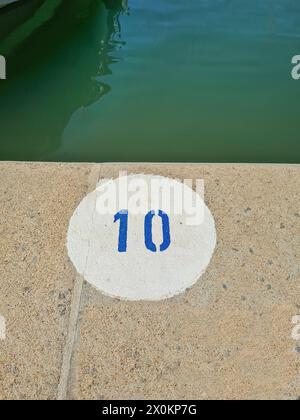 Ein weißer runder Kreis mit der blauen Zahl 10, Markierung auf Steinboden, Hafen, Mallorca, Spanien Stockfoto