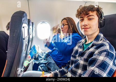 Eine Familie sitzt zusammen an Bord eines Flugzeugs, eines EasyJet Fluges. Ein Teenager sitzt neben seiner Mutter und lächelt nach der Kamera Stockfoto