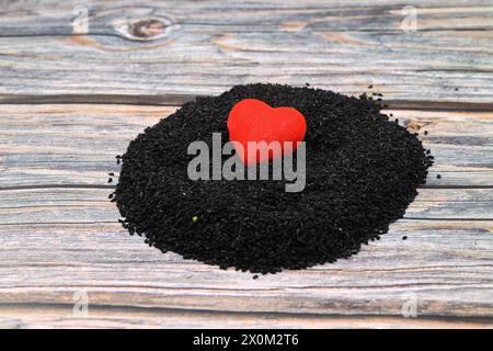 Schwarzer Kreuzkümmel und ätherisches Öl mit Schale und Holzschaufel oder Löffel. Nigella Sativa in Glasflasche. Bio-Kräutermedizin für viele Krankheiten Stockfoto