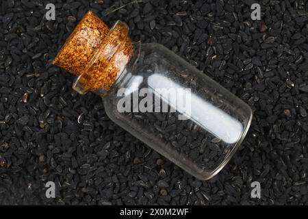 Schwarzer Kreuzkümmel und ätherisches Öl mit Schale und Holzschaufel oder Löffel. Nigella Sativa in Glasflasche. Bio-Kräutermedizin für viele Krankheiten Stockfoto