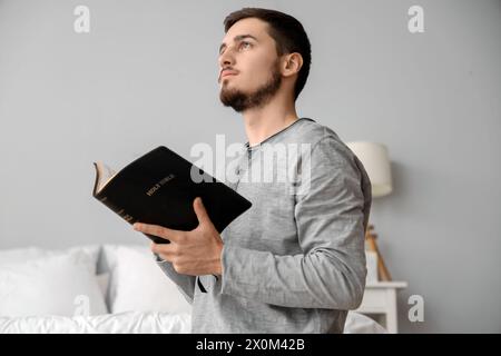 Junger Mann, der im Schlafzimmer Bibel liest Stockfoto