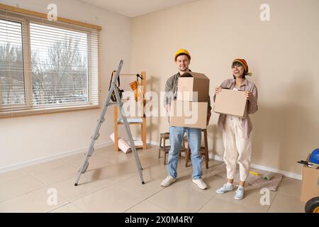 Ein junges Paar mit Kisten während der Reparatur in ihrem neuen Haus Stockfoto